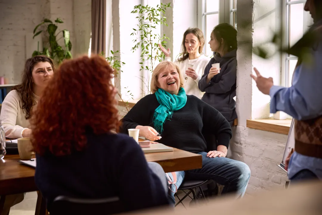 Senior businesswoman laughing during friendly team conversation.